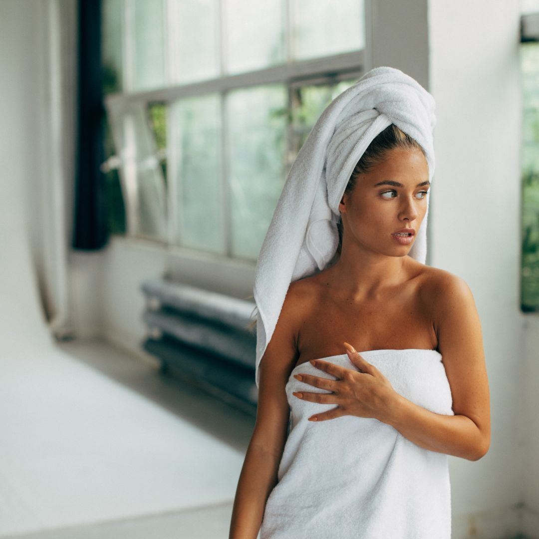 Woman wrapped in a white towel in a bright room