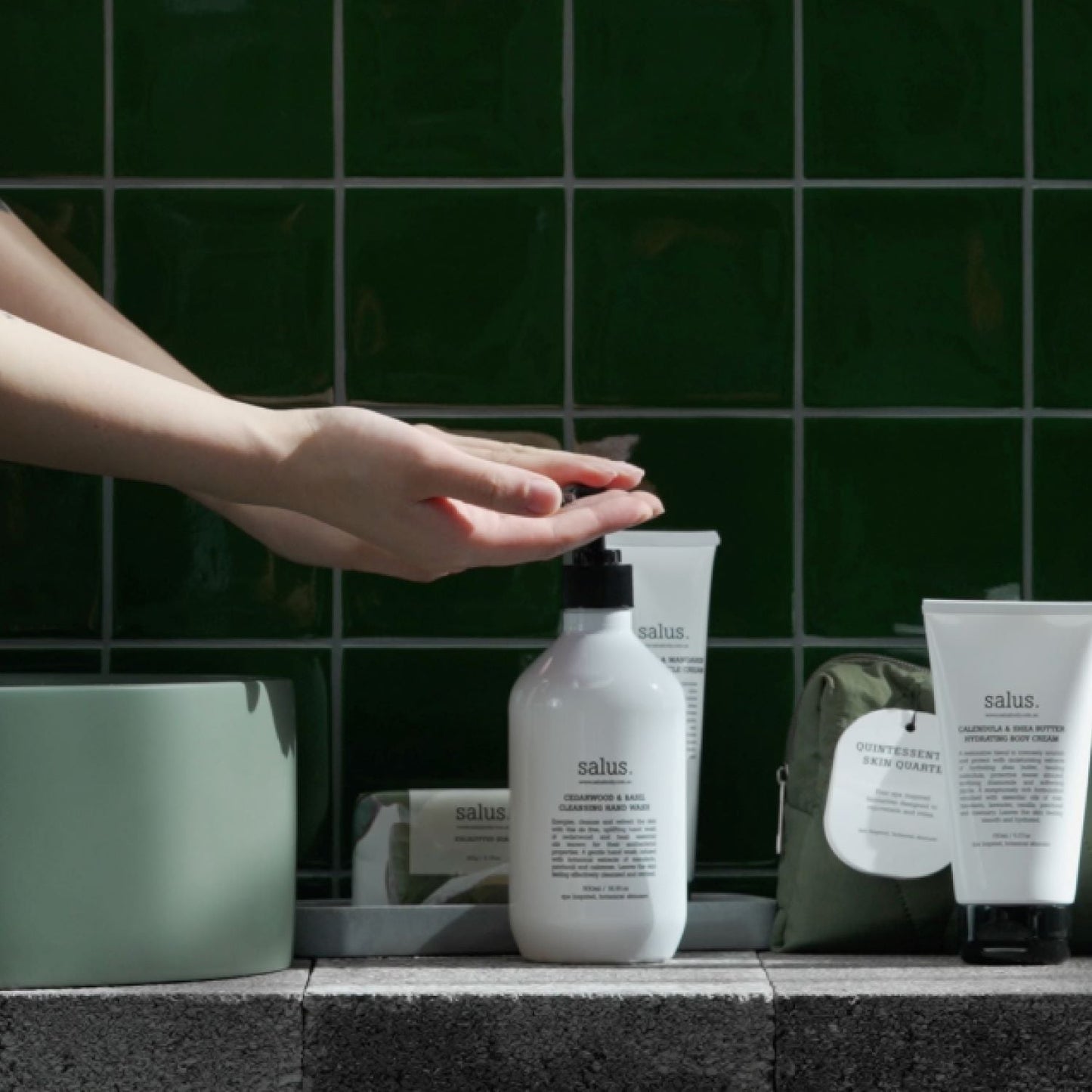 Person applying soap from a bottle with 'nuskin' branding against a green tiled wall.